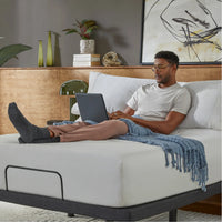 Man using a laptop on a bed in a bedroom setting